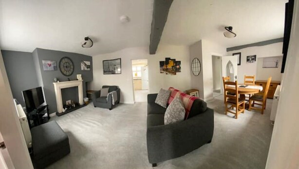 Ein Wohnzimmer mit Sofa, Kamin, Essbereich mit Tisch und Stühlen sowie einem Fernseher.