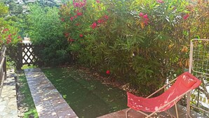 A garden with a pathway, a red chair, and a fence. - Appartement Avec la Piscine Privée (Cavalaire-sur-Mer)