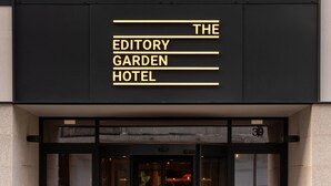 Exterior del Hotel The Editory Garden, con una fachada moderna y una entrada despejada.