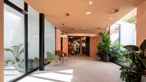 Un interior moderno con una pared de vidrio, una silla verde y plantas en macetas.