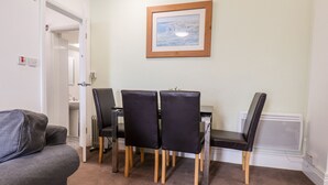 Un coin repas avec une table et des chaises, un tableau encadré au mur et un radiateur.