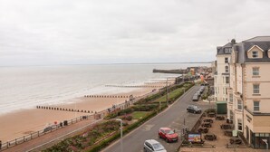 Une route côtière bordée d’un côté par une plage, et de l’autre par des bâtiments et une promenade.