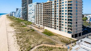 Un hôtel à plusieurs étages, doté de balcons, offrant une vue sur la plage et disposant d’un parking.