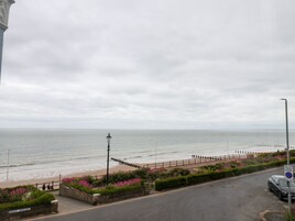 A coastal road with a pedestrian path, a beach, and a 'Pay and Play Zone' sign.