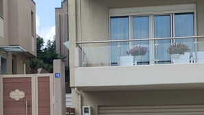 Un immeuble résidentiel à plusieurs étages, doté d’un balcon, de plantes en pot et d’une porte de garage.