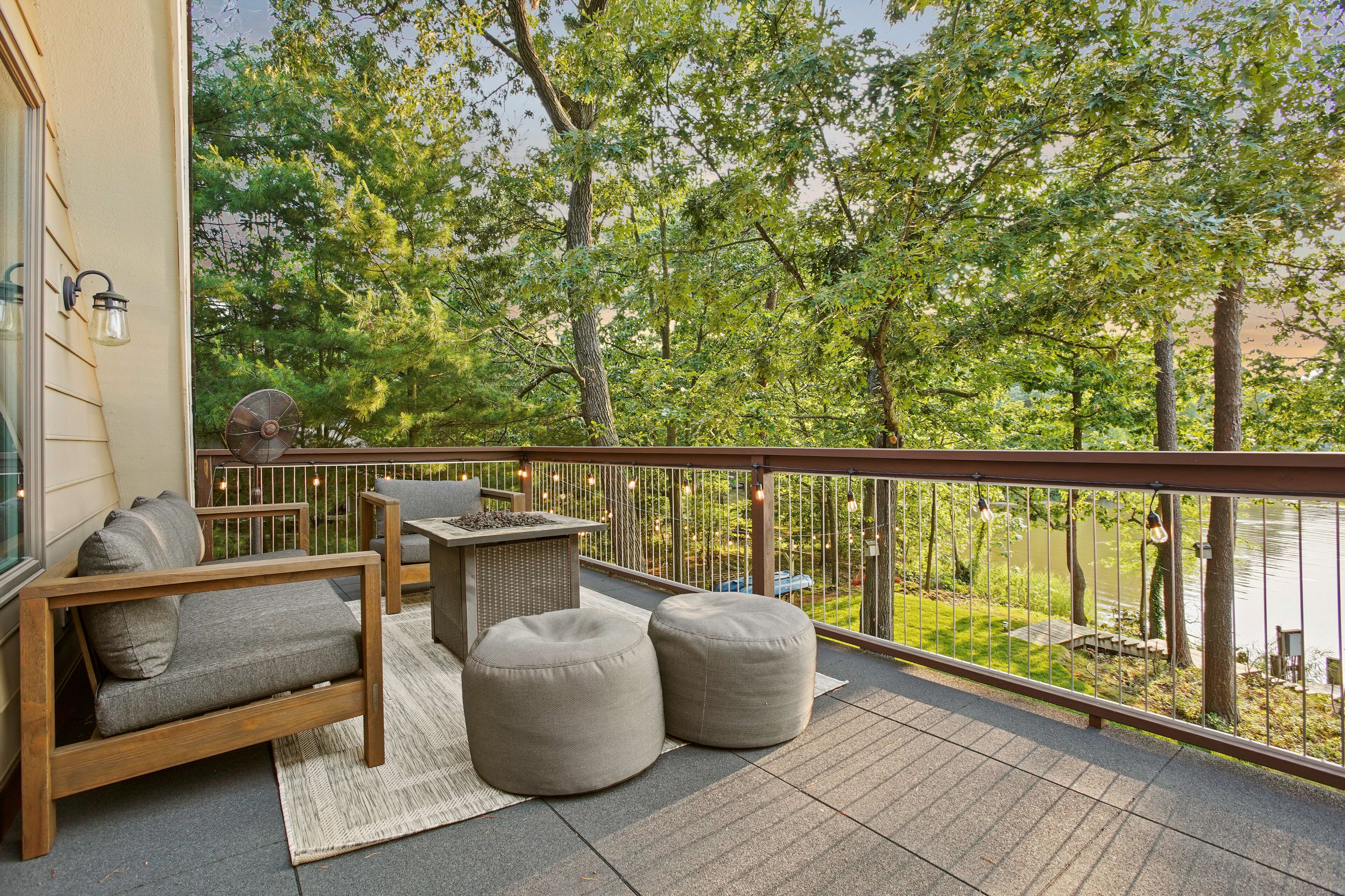 A balcony with a wooden sofa, two ottomans, a small table, and a chair.