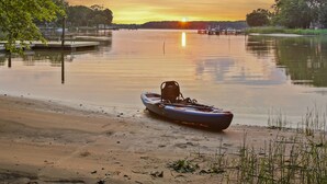 A calm lake at sunset with a kayak on the shore. - Harbor View Haven | Waterfront w/ Hot Tub + Dock! (Chestertown)