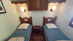 A room with two single beds, each with a heart-shaped headboard, a small bedside table, and wall-mounted lights. - Cozy south-facing apartment, 4 people, near funicular (Isola 2000)