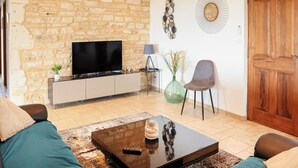 A living room with a stone wall, a flat-screen TV, a coffee table, a sofa, and a door.