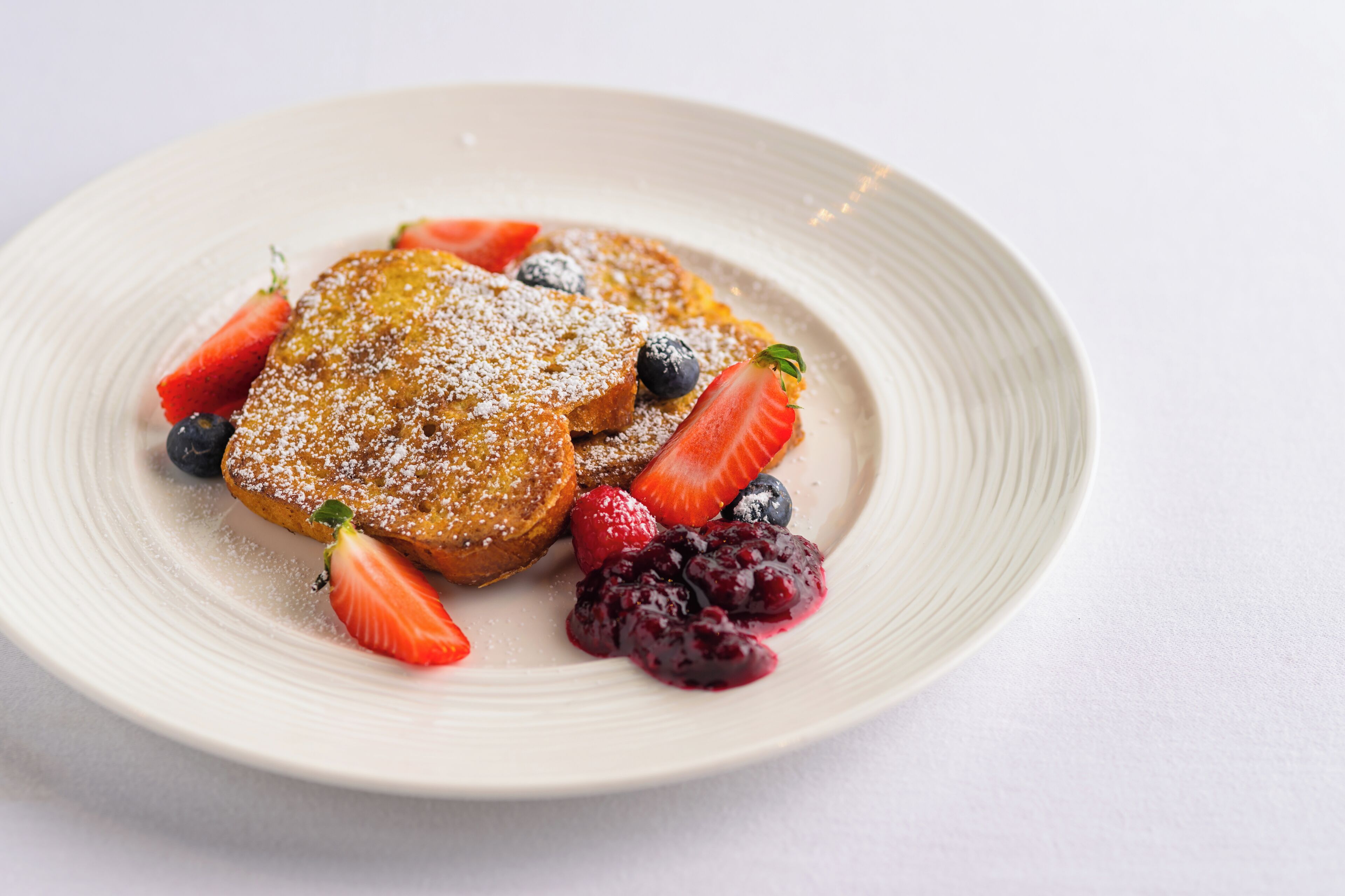 A plate of French toast with strawberries and blueberries.