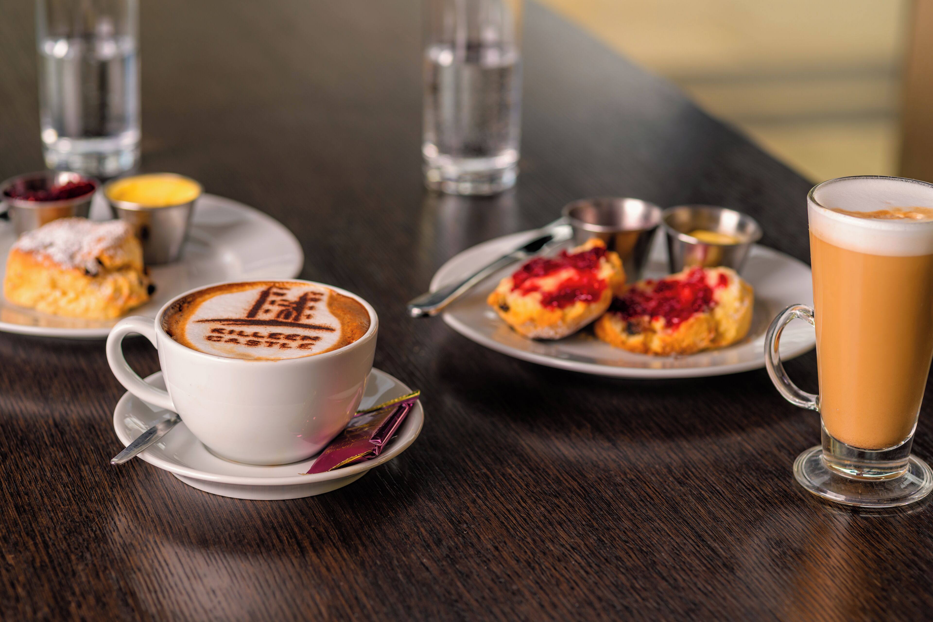 Une table avec une tasse de café, un verre de bière et des assiettes de pâtisseries.