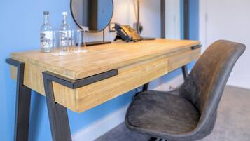 A wooden desk with a mirror, two bottles, and a lamp.