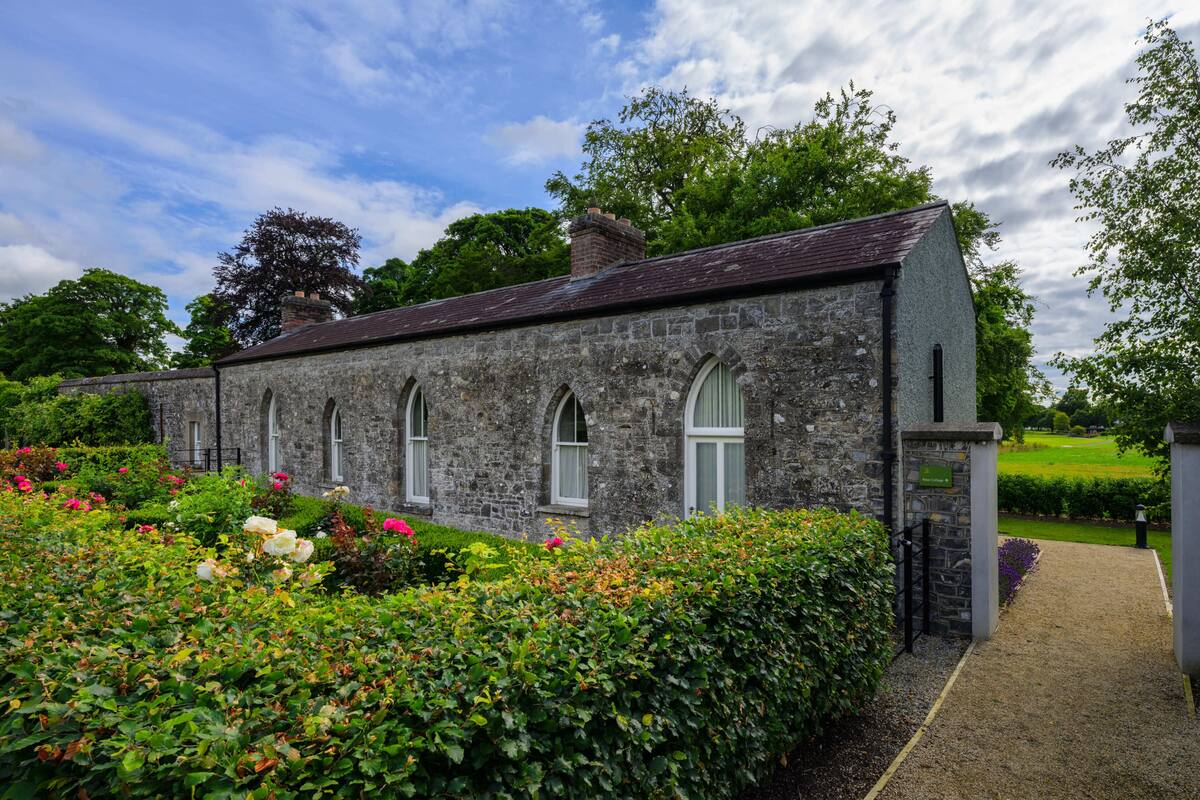 A stone building with arched windows and a gravel pathway leading to a gate.