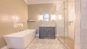 Un baño moderno con una bañera independiente, un tocador con espejo y una ducha con mampara de vidrio.