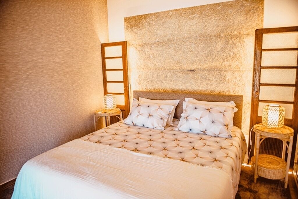 A bed with a tufted headboard, two bedside tables with lamps, and a textured wall.