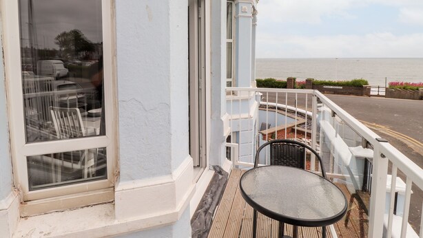 Un balcon avec une table et des chaises, donnant sur une étendue d’eau.
