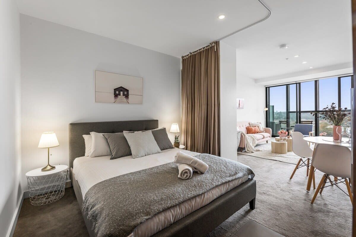 Una camera d'albergo moderna con un letto grande, una scrivania e vista sulla città.