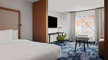 Habitación de hotel con una cama grande, un escritorio con silla, un televisor y una ventana con cortinas.