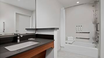 A modern bathroom with a sink, mirror, and shower.