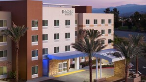 A multi-story hotel with a modern design, featuring a prominent entrance with a blue awning and palm trees. - Fairfield Inn by Marriott & Suites Chino (Chino)
