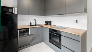 Una cocina moderna con gabinetes grises, un refrigerador negro, horno integrado y un microondas.