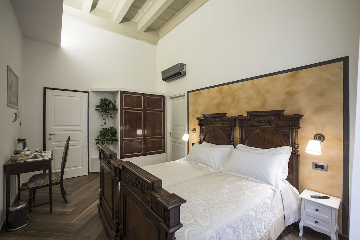 A bedroom with a wooden bed, a nightstand, a desk, and a chair.