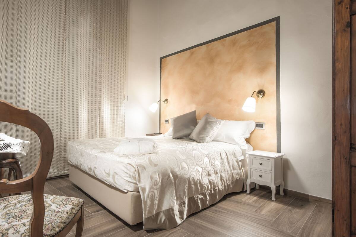 A bedroom with a large bed, a bedside table, and a nightstand.