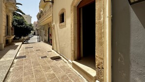A narrow street with buildings on both sides, a tiled pavement, and a door with a red frame. - City Center 1-bed House in Heraklion (Heraklion)