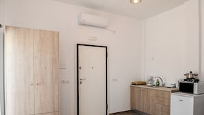 A compact kitchen with a microwave, a small refrigerator, and a wooden wardrobe. - Santorini Life Vibrant Studio Only 50m from the Beach (Perissa Santorini)