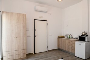 A compact kitchen with a microwave, a small refrigerator, and a wooden wardrobe. - Santorini Life Vibrant Studio Only 50m from the Beach (Perissa Santorini)
