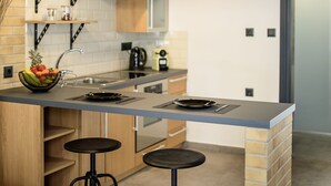 A modern kitchen with a central island, stools, and a loft bedroom above. - Loft 2 (Kos)