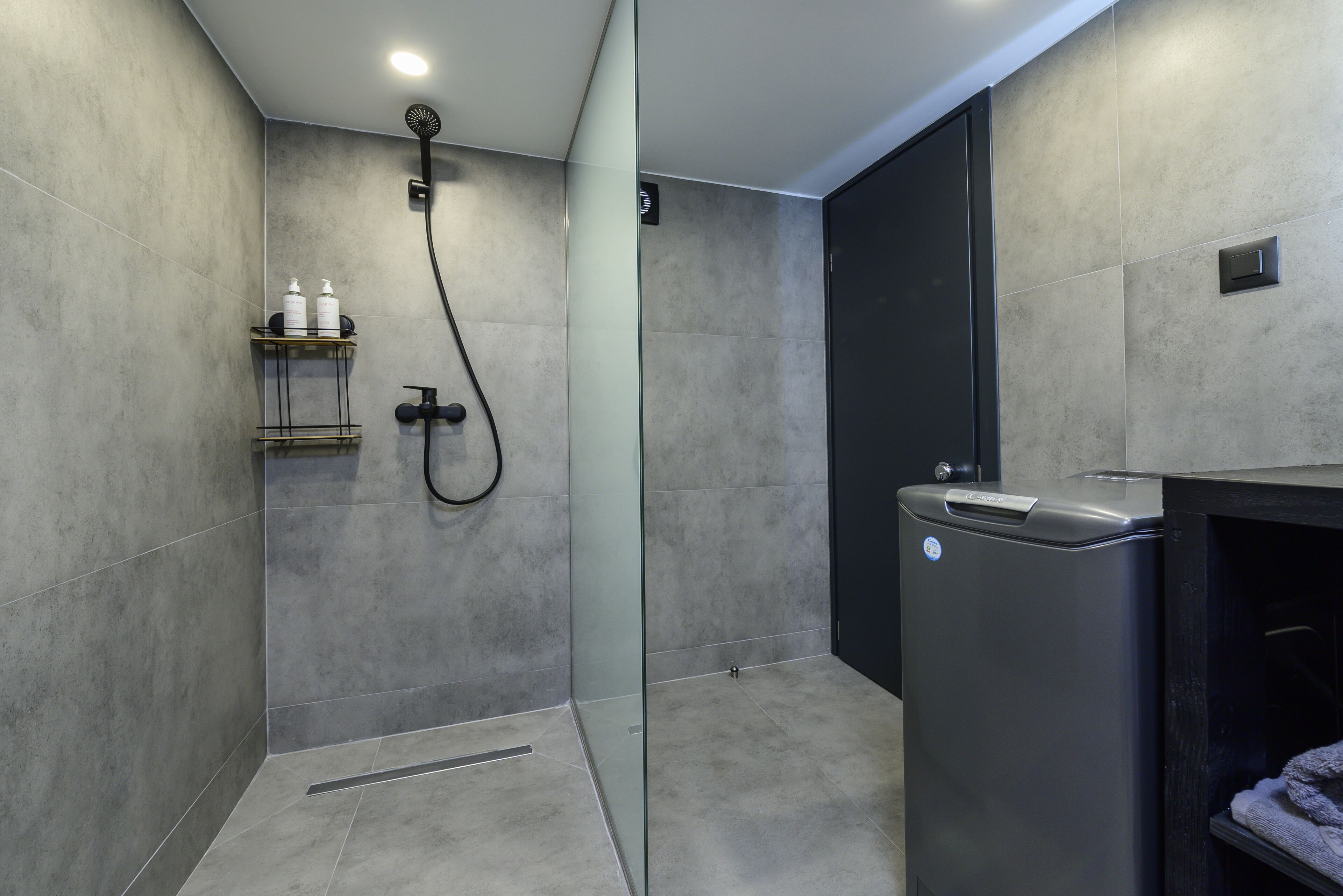 A modern bathroom with a glass-enclosed shower, a black vanity, and a towel rack.