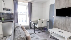 A modern living room with a sofa, dining table, and TV. - Ocean Wave (Bridlington)