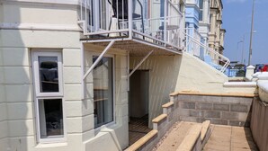 Ein Gebäude mit weißer Fassade, einem Fenster und einer kleinen Außenfläche mit Stufen, die zu einem Balkon führen.