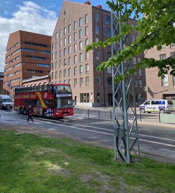 A red double-decker bus on a city street with buildings in the background.