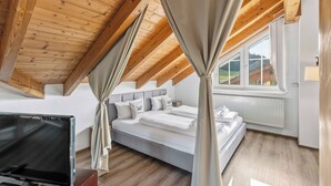 A bedroom with a sloped ceiling, a bed, a TV, and a window with a view of the outdoors. - 2 bedroom apartment in buchenberg (Buchenberg)