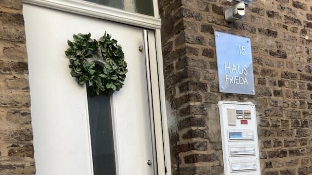 A white door with a green wreath, a sign reading "15 HAUS FRIEDA", and a utility box with a metal handle. - 1 Bedroom Apartment in Bonn (Bonn)