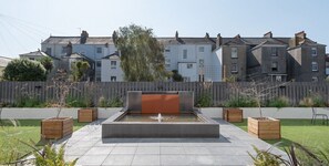Stroll through a serene outdoor oasis with a tranquil water feature and lush greenery.