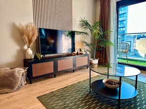 Relax in this stylish living room with a large flat-screen TV, plush sofa, and a beautiful view of the surrounding area.
