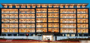 Experience the sleek, modern design of this hotel, featuring a symmetrical facade with evenly spaced windows and balconies on each floor.