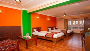 A hotel room with two beds, a wooden floor, a small table with a vase, and a chair. - MeroStay 201 MD HOTEL (Kathmandu)