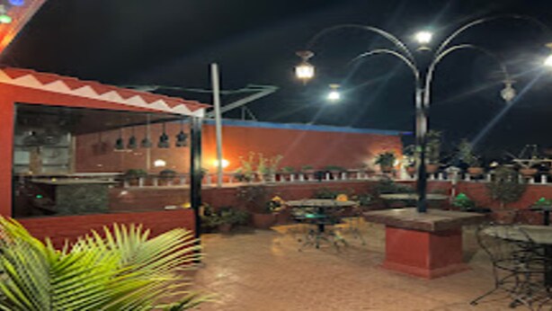 An outdoor patio area with tables and chairs, a bar area, and potted plants. - MeroStay 201 MD HOTEL (Kathmandu)