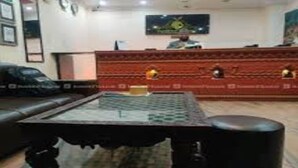 A reception area with a red counter, a television mounted on the wall, and a black leather sofa. - MeroStay 201 MD HOTEL (Kathmandu)