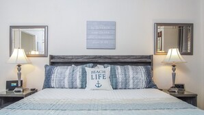 A neatly arranged bedroom with a bed, two bedside tables, two lamps, and a wall-mounted sign. - Outstanding Oceanfront unit with a Breathtaking View - Sonoran Sun E-511 (Puerto Peñasco)