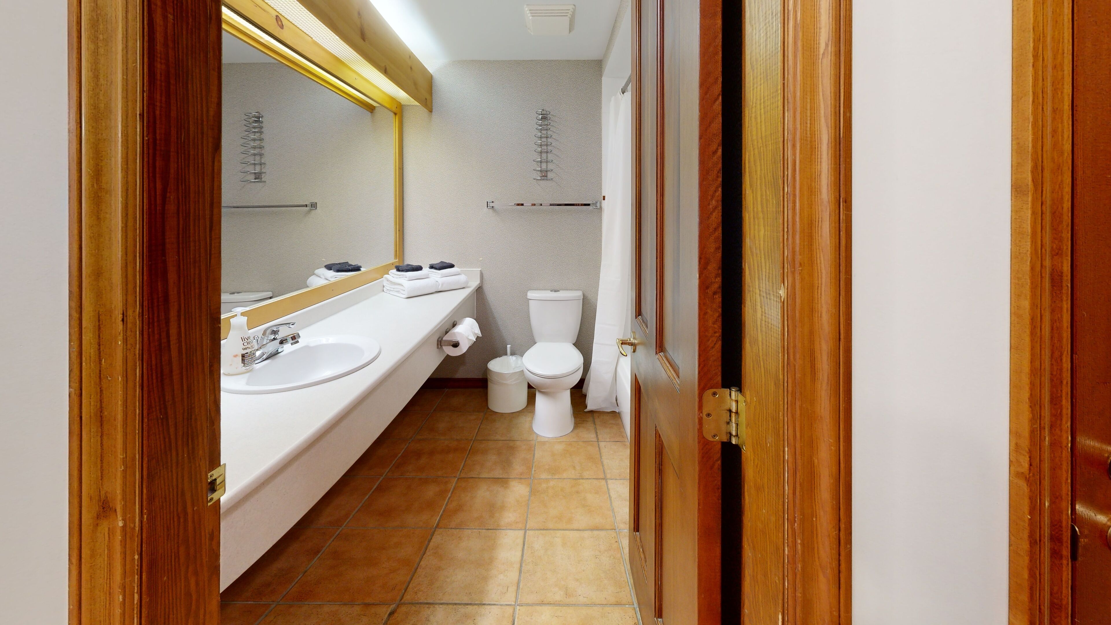 Un baño con lavamanos, espejo y retrete blancos.