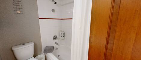 A bathroom with a toilet, shower, and a shelf with toiletries.
