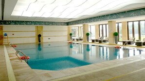 An indoor swimming pool with clear water, a tiled floor, and a ceiling with wavy lines. - Ondine Oriental International Hotel (Zhenjiang)