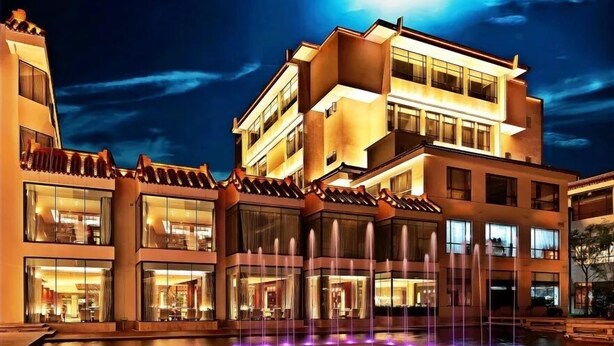 A modern hotel with a water feature in front, multiple balconies, and large windows. - Ondine Oriental International Hotel (Zhenjiang)