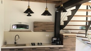 A modern kitchen with wooden cabinets, a round dining table, and white chairs. There is a built-in oven and a coffee maker on the counter. - Treat yourself to a true escape, far from the noise and the everyday routine. (Marcilly-en-Gault)