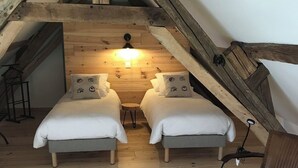 A loft bedroom with two beds, wooden beams, a hanging light, and a chair. - Treat yourself to a true escape, far from the noise and the everyday routine. (Marcilly-en-Gault)